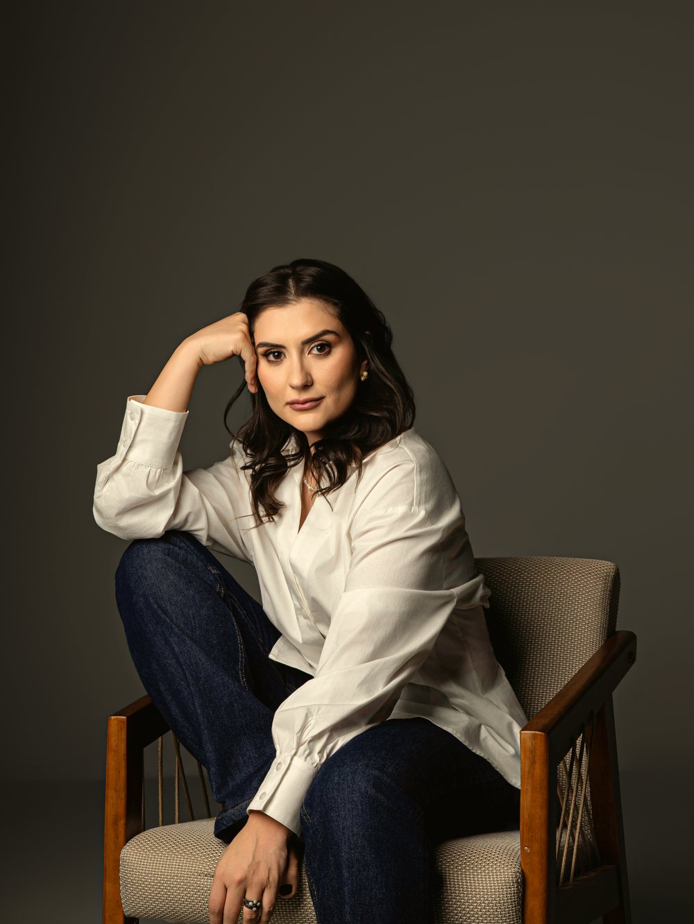 Dra. Marcella Pagnano Bocchi sentada em uma cadeira de madeira, sorrindo, retrato de luz natural
